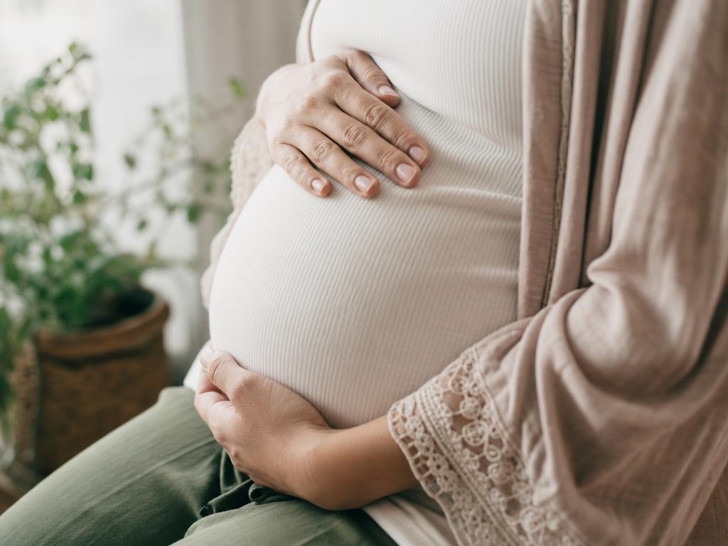 A pregnant person gently cradling their belly