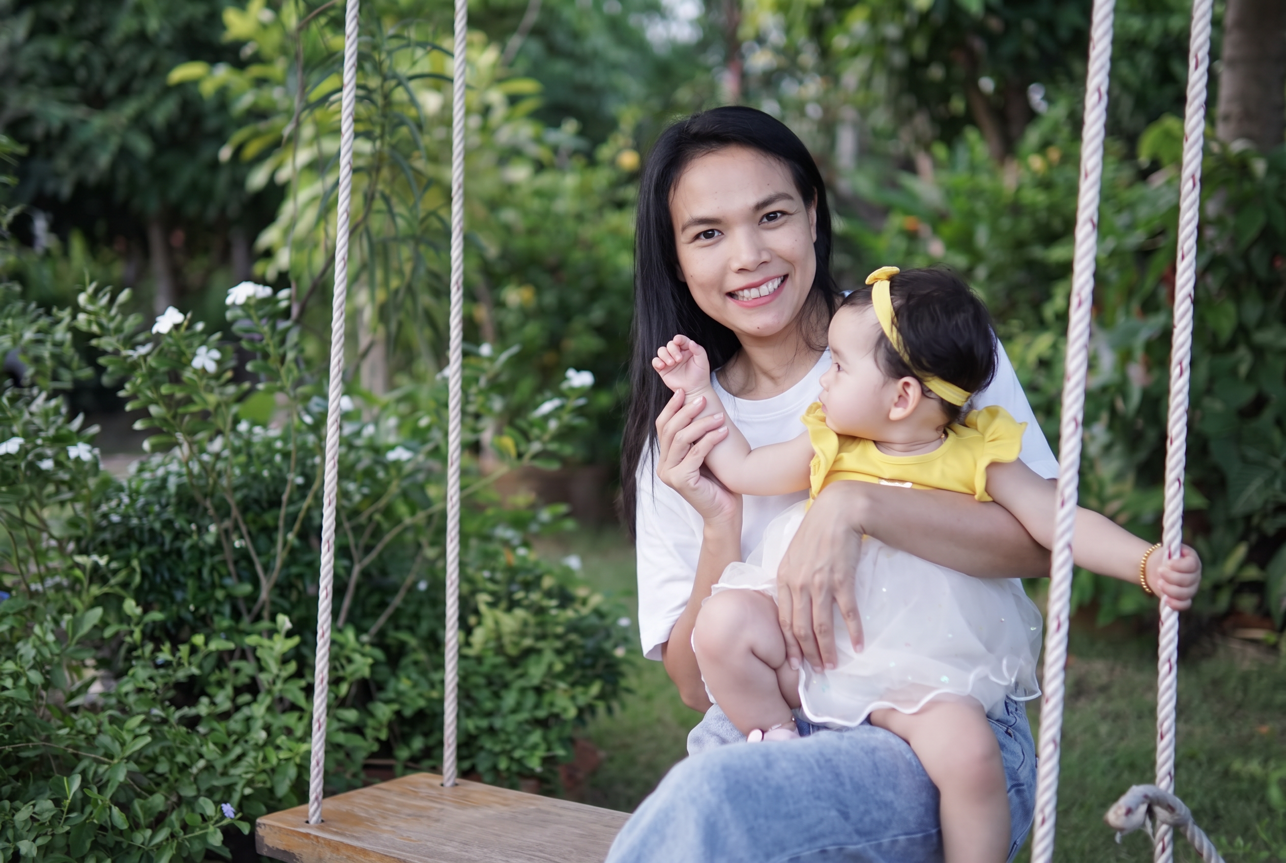 Sudarat sitting on a garden swing holding a baby